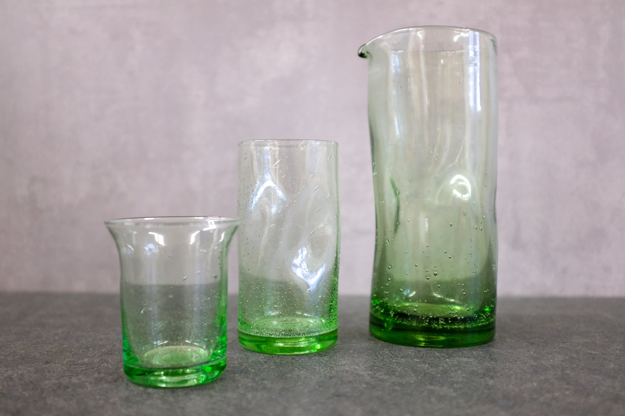 Goetheglas Waldglas, Trinkglas Bauhaus und Wasserkrug nebeneinander.