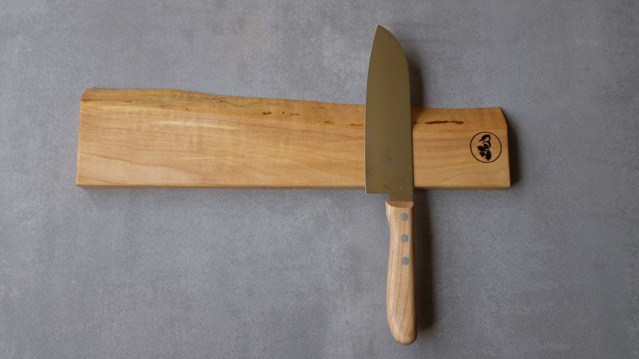 Mit Baumkante in Vogelbeere massiv. Messerhalter für 7 Messer. Mit einem Windmühlenmesser Santoku an einer Betonwand montiert.