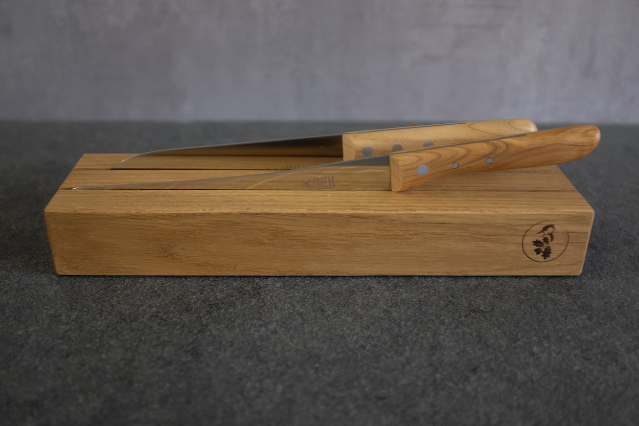 Messerhalter, zweifach, aus Eichenholz. Dekoriert mit einem Windmühlenmesser Santoku und einem Brotmesser, lang.