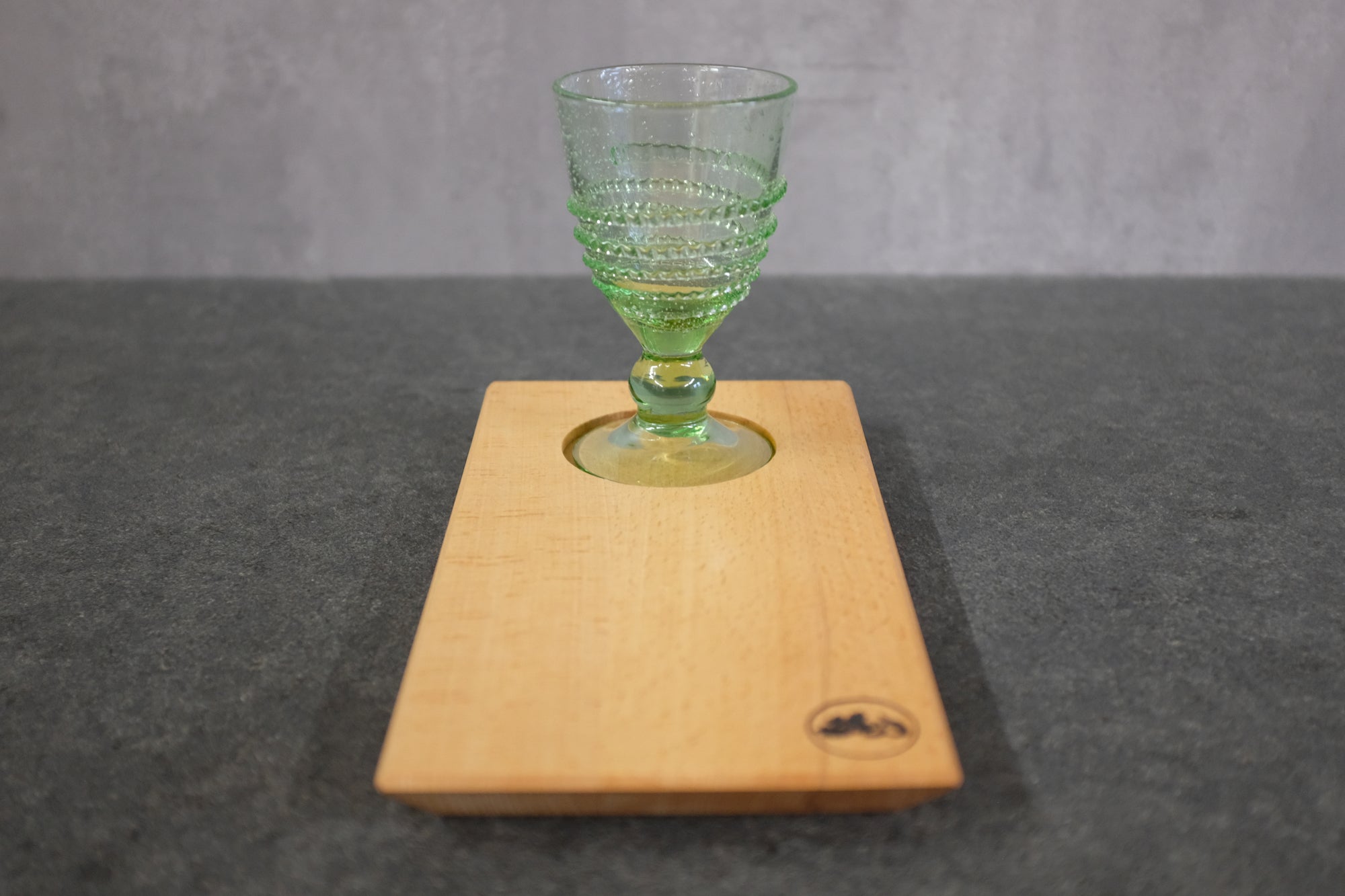 Weinglas aus Waldglas von der Farbglashütte Lauscha auf einem Holztablett aus Buche.